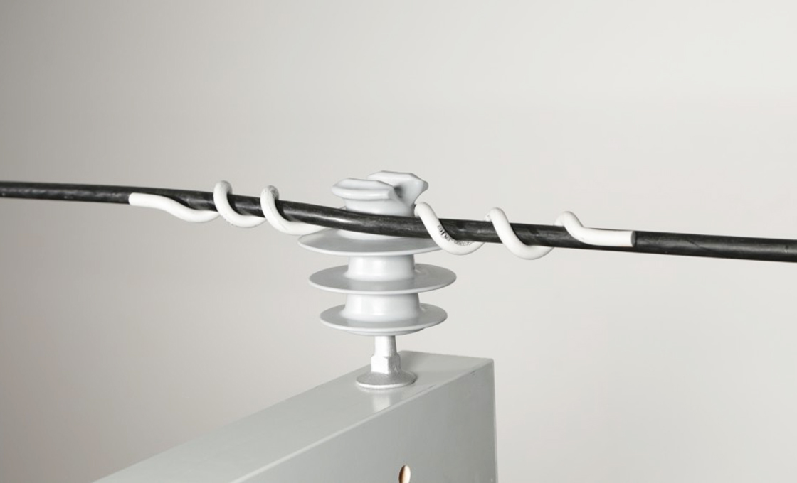 Plastic-covered insulator tie holding a conductor in a pin insulator groove