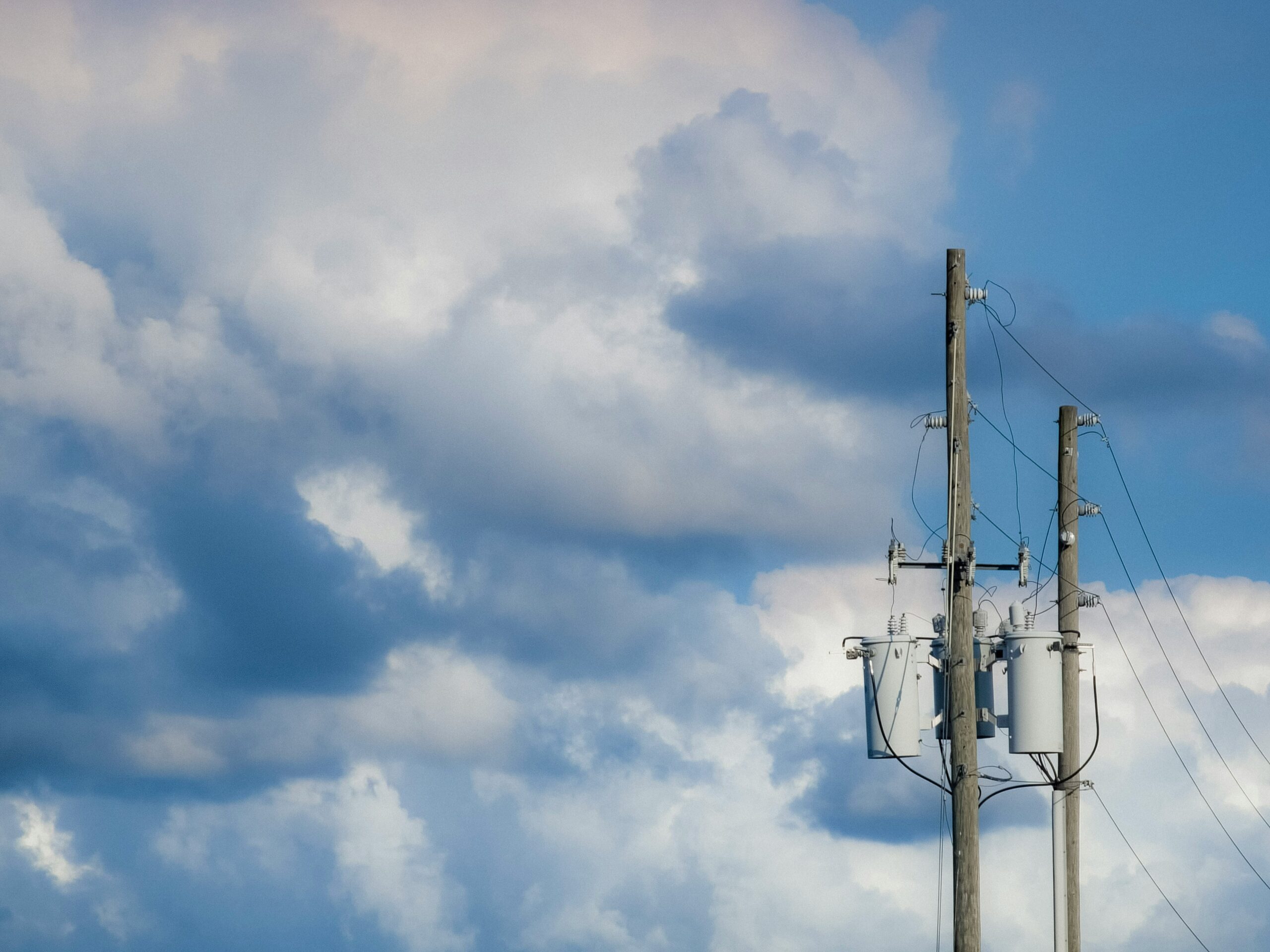 A utility pole with a transformer against a cloudy sky.
