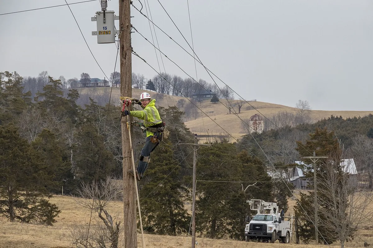 Lineman climbing a utility pole to re-check newly fitted hardware