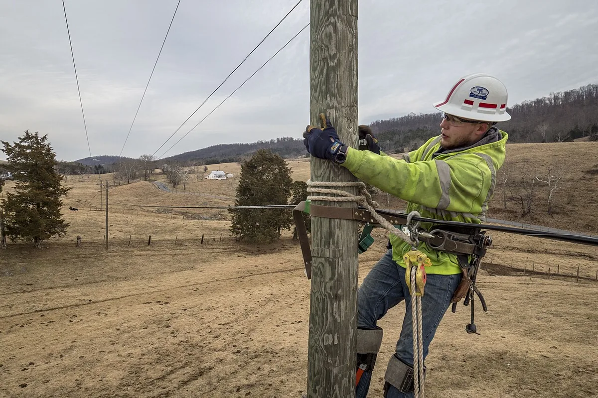Lineman in a belted work position on a wood pole during hardware fitting