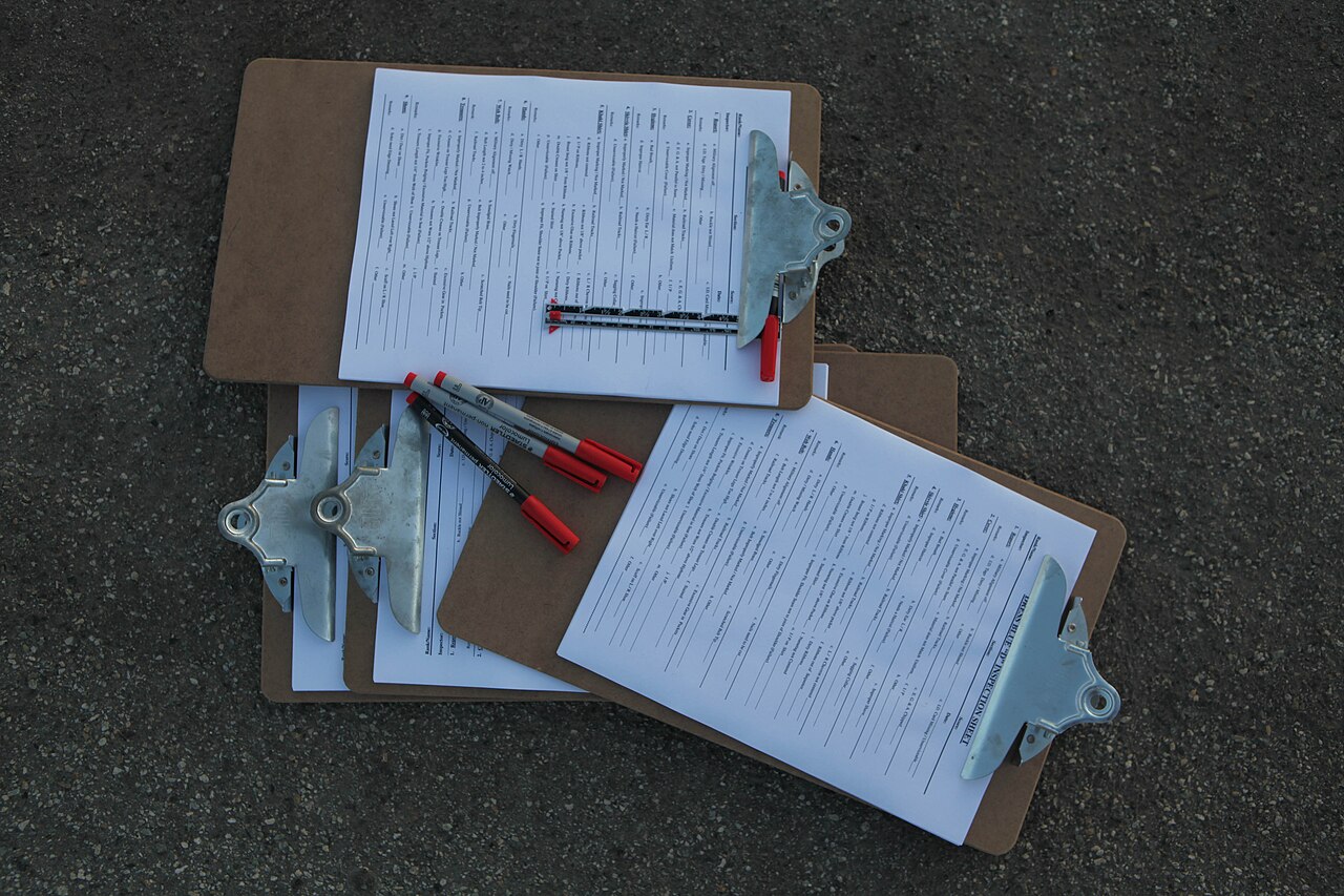 Printed audit checklists on clipboards laid out on the ground