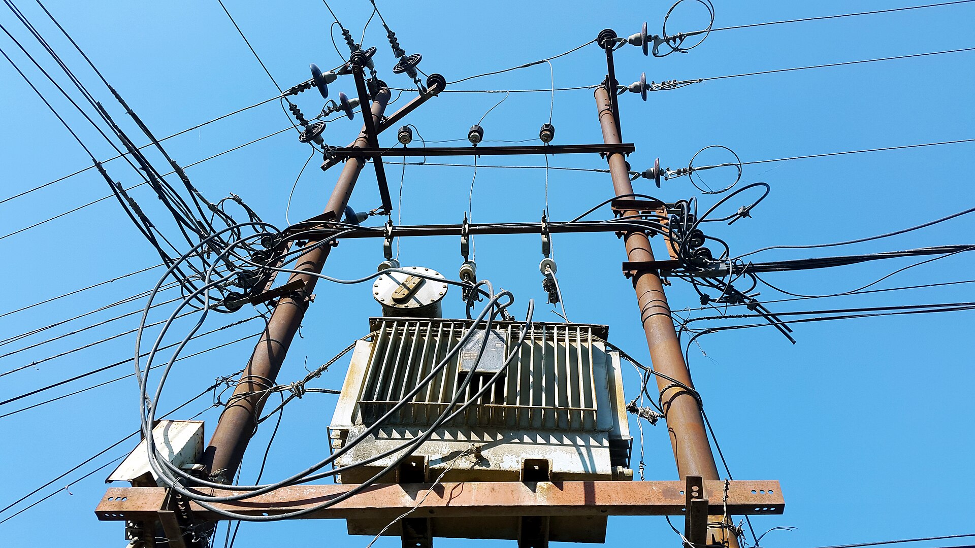 Distribution pole top with several crossarms carrying pin insulators