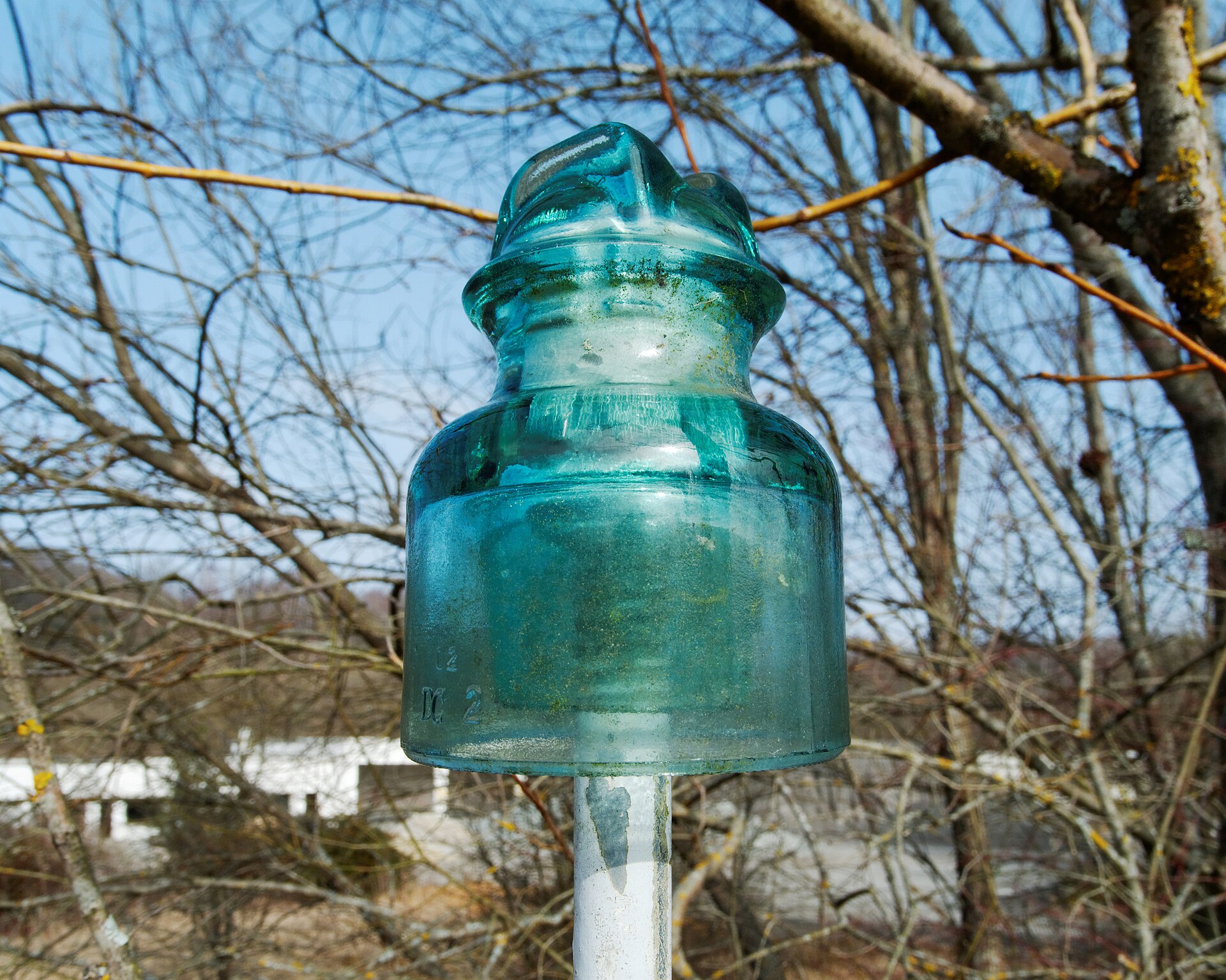 Skirted glass pin insulator mounted on its steel pin outdoors