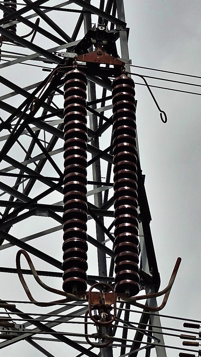 Twin porcelain suspension insulator strings with arcing horns seen from the tower