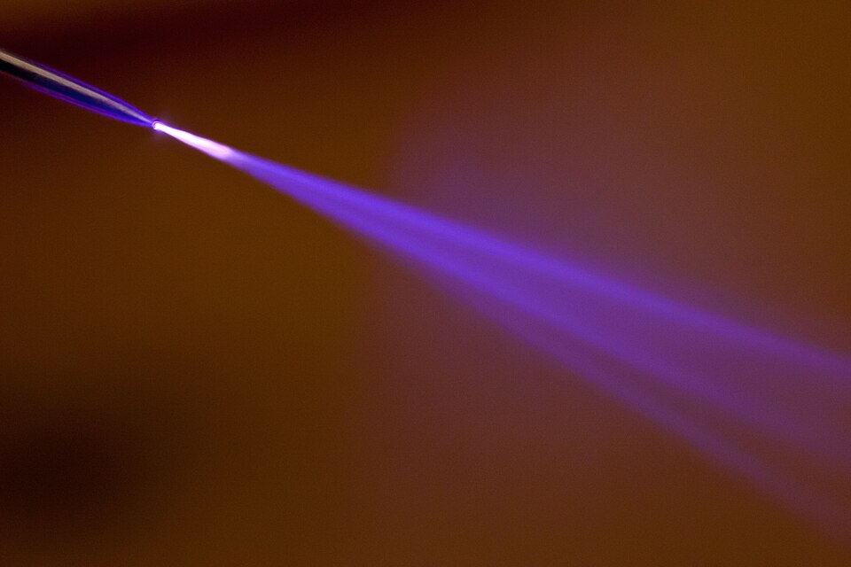 Violet corona cone leaving the tip of a pin at 15 kV