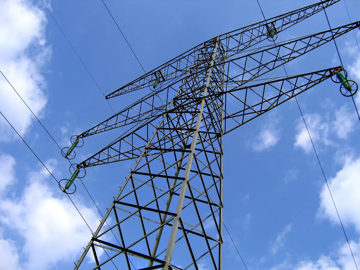 Lattice transmission tower with loaded crossarm arms under clear sky