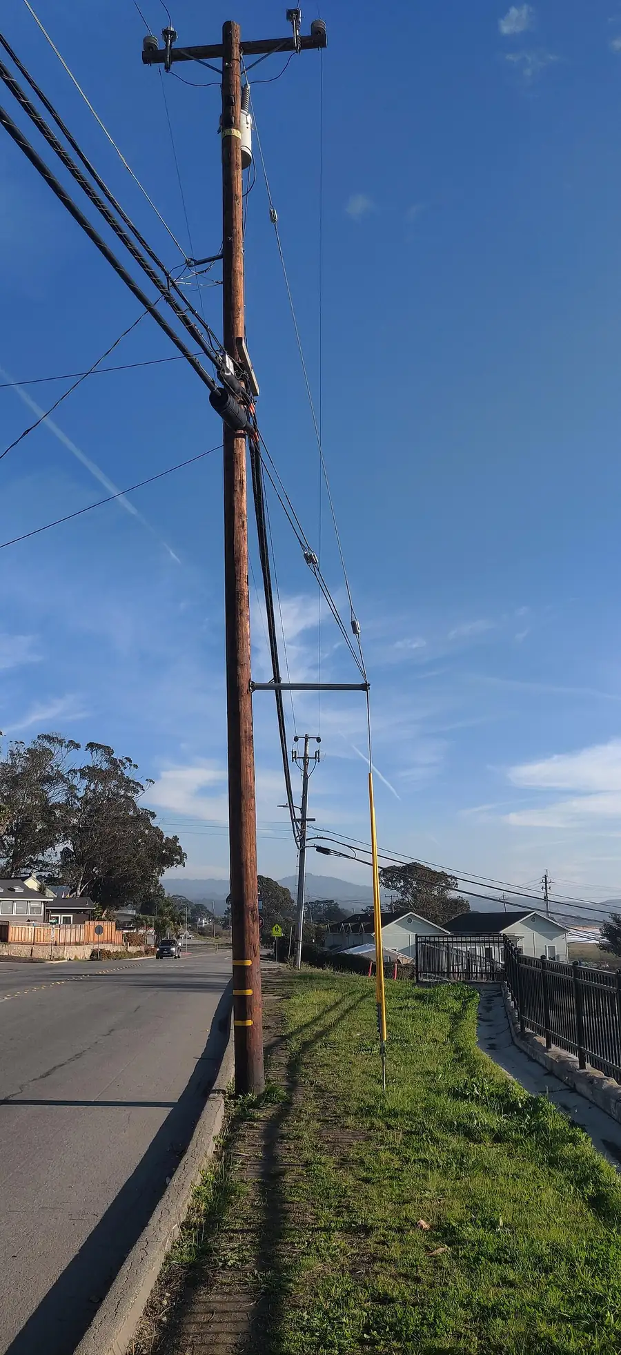 Wooden distribution pole with sidewalk guy wire and yellow guard