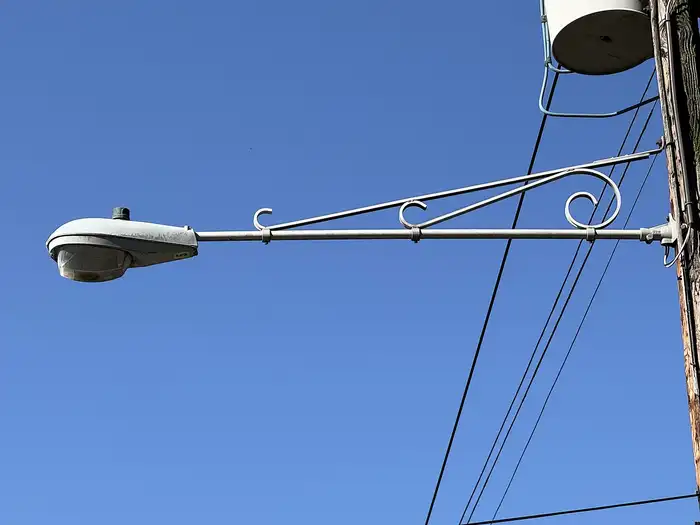Street light mast arm carrying a luminaire on a wooden pole