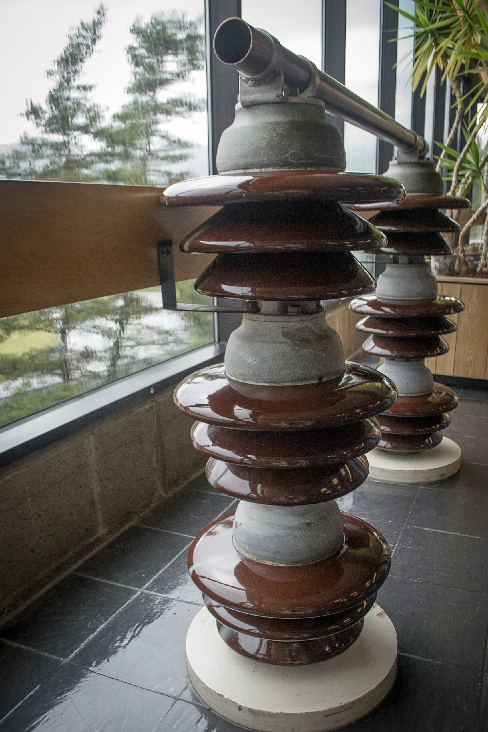 Stacked brown porcelain post insulators carrying a bus pipe