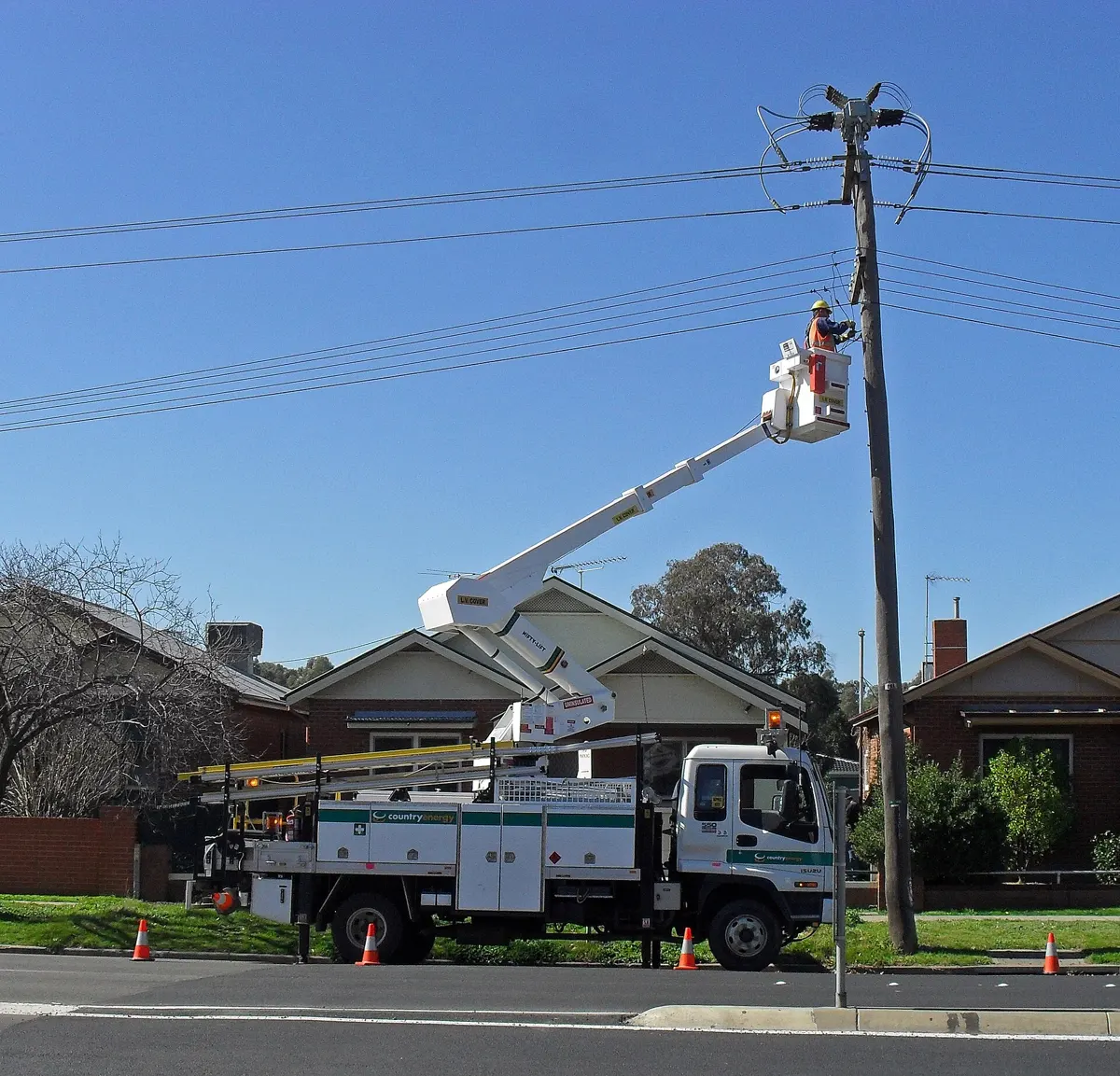 Utility crew in a bucket truck working on a wood distribution pole