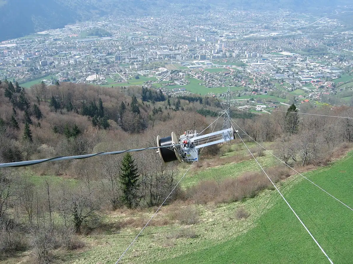 Fiber optic cable being installed along a long overhead span in hilly terrain