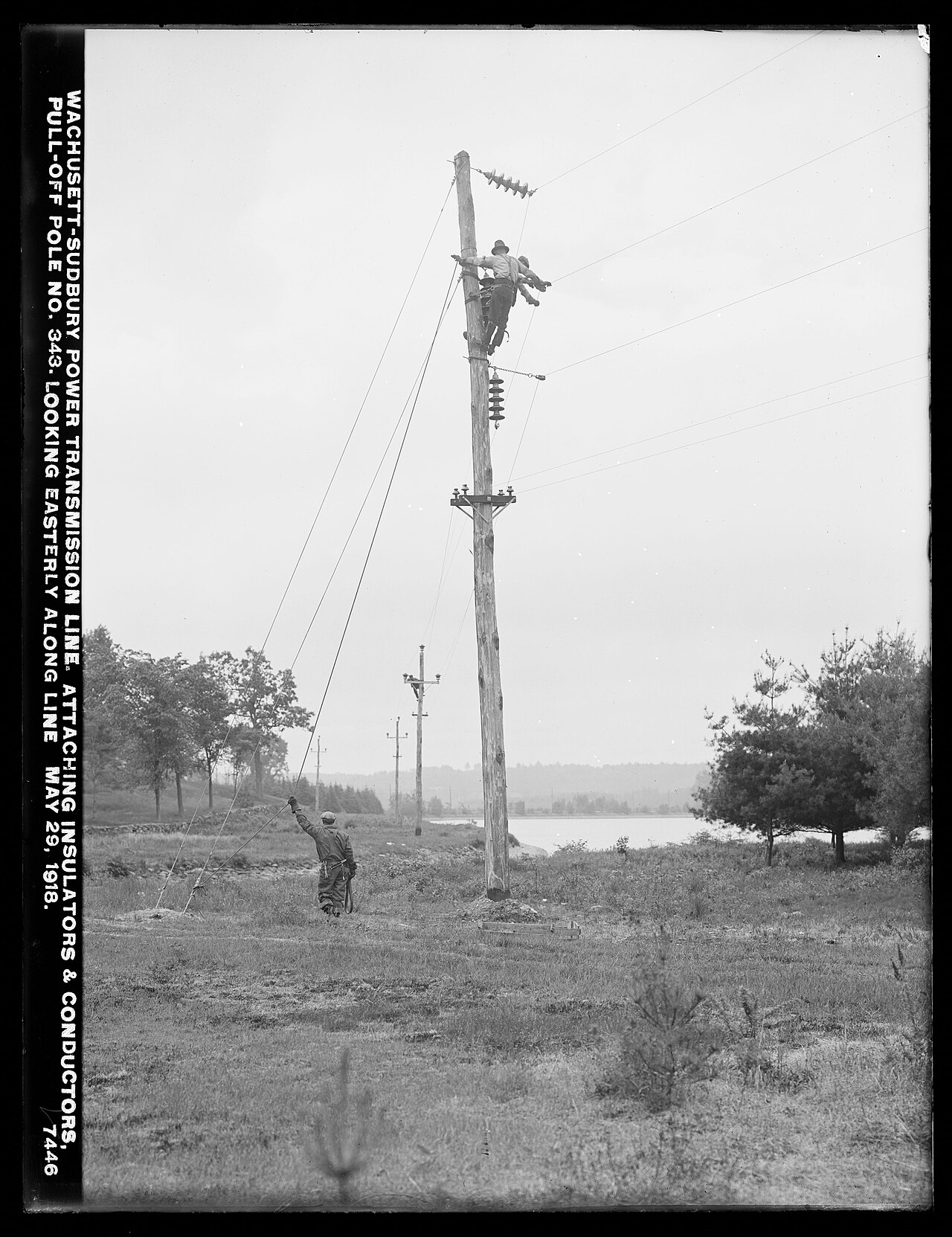 Linemen stringing conductors on an early wooden transmission pole