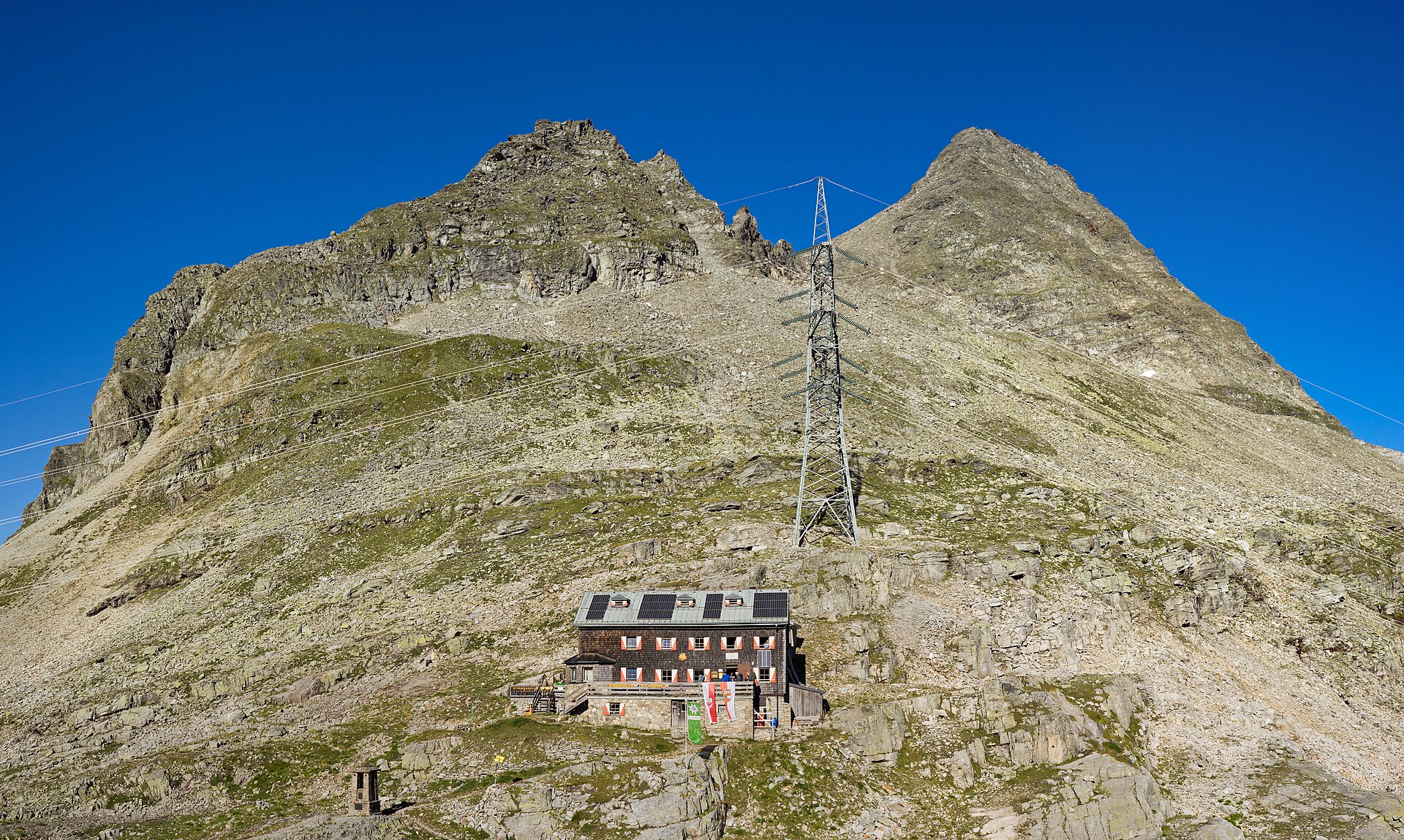 Transmission tower and overhead lines climbing an alpine mountainside